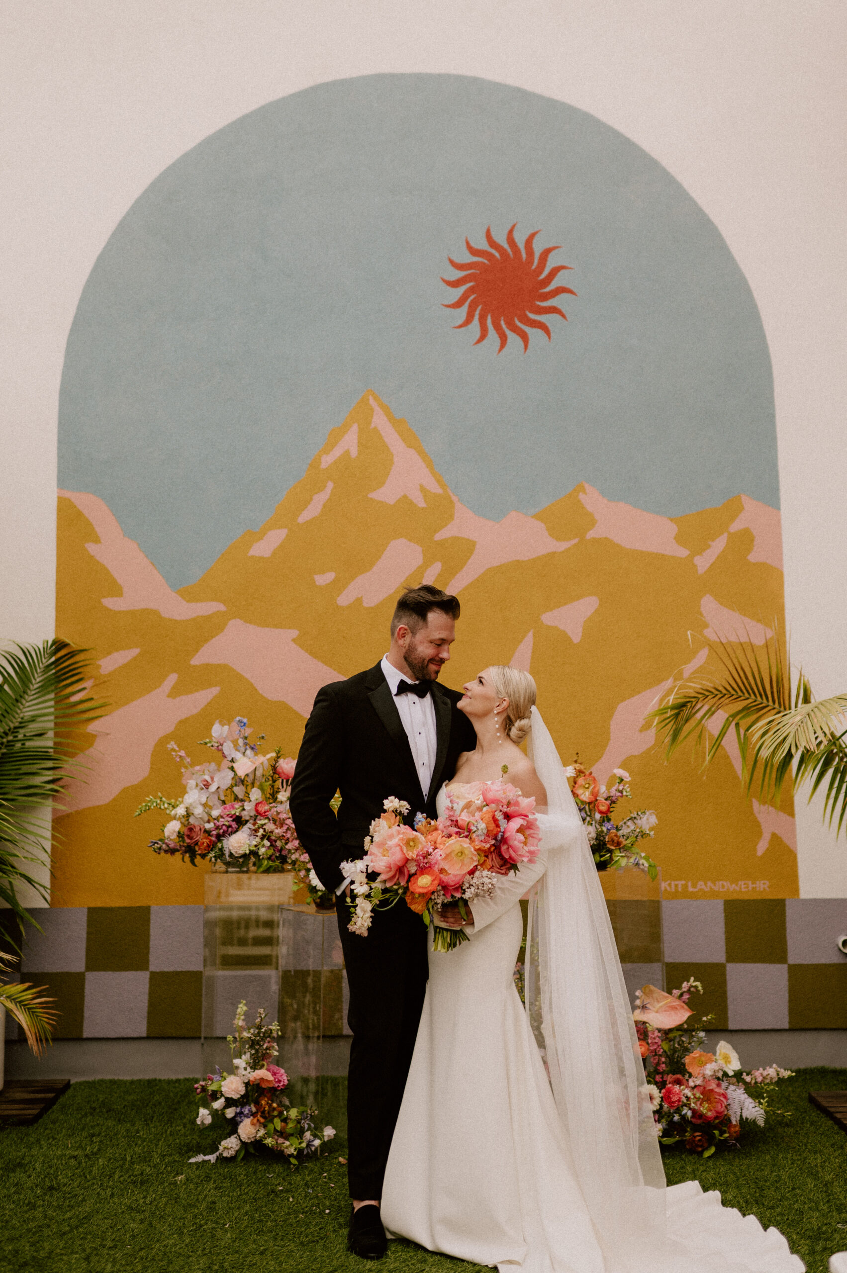 bride and groom in front of mural at Hotel No Vacancy