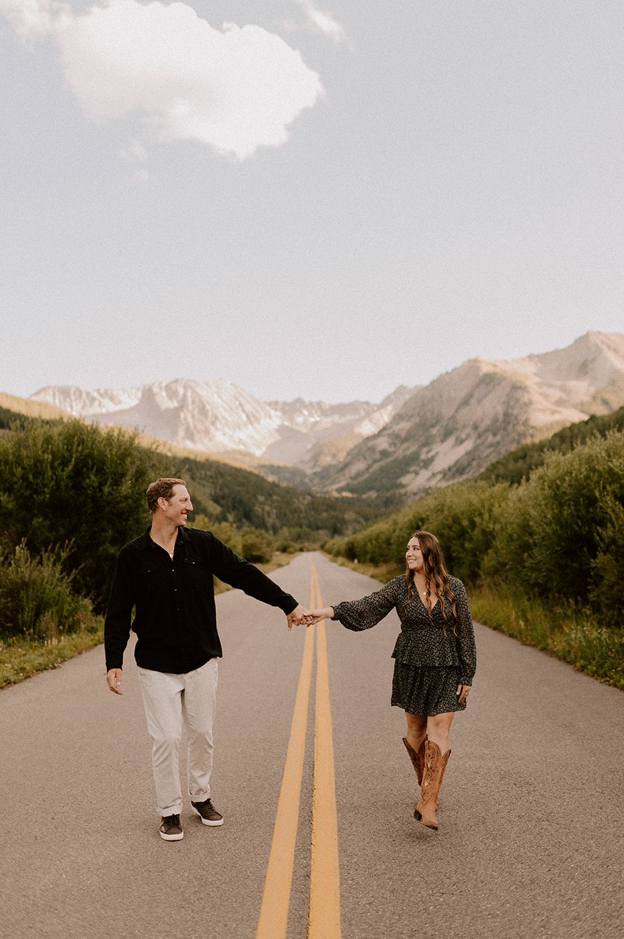 engagement session couple walking down middle of street mountains